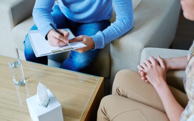 Male psychologist making notes during psychological therapy