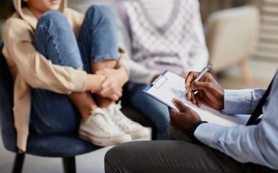 Close up of African-American psychologist taking notes on clipboard in therapy session for children